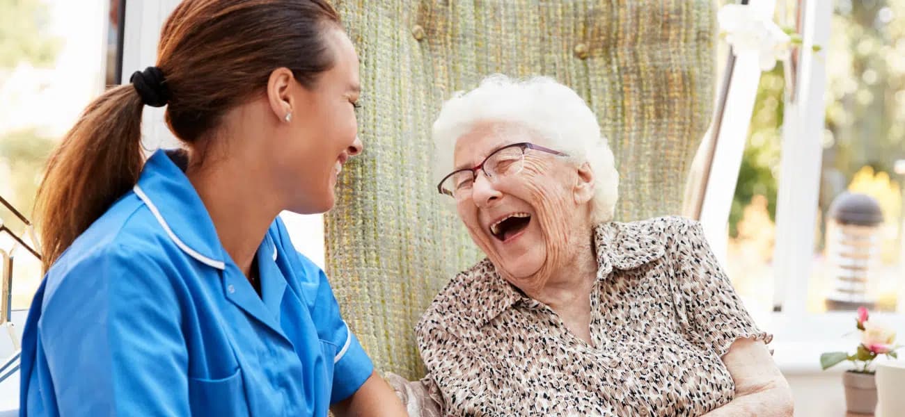 A nurse and an older woman laughing together at a Tucson care community