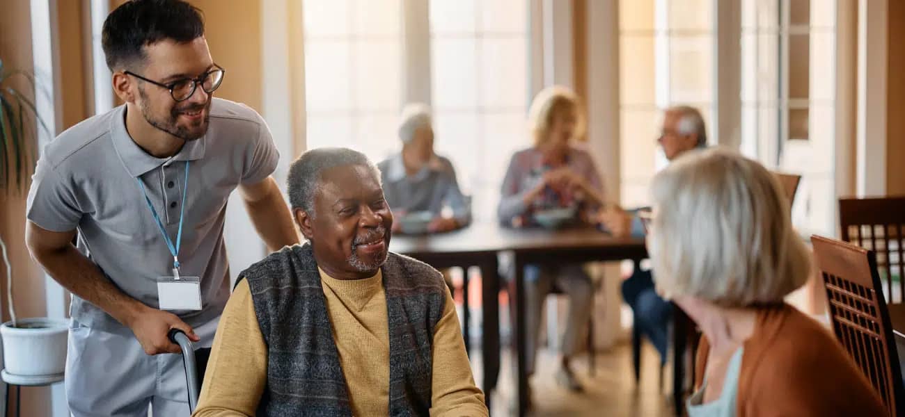 A care advisor speaking with a senior resident in a Tucson care community dining room
